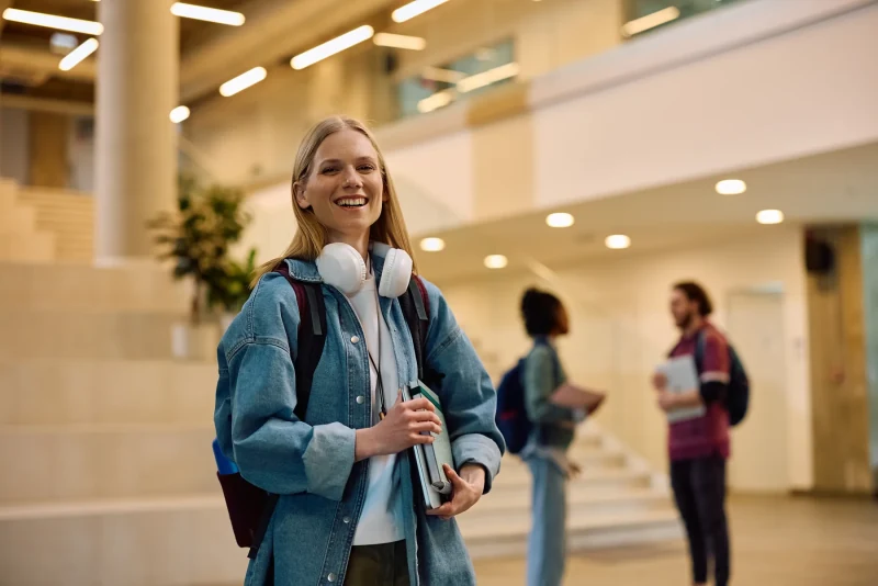Student with a backpack and headphones in a campus hallway